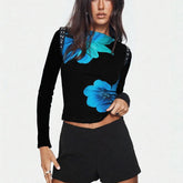 Woman wearing a black long-sleeve top with blue floral designs